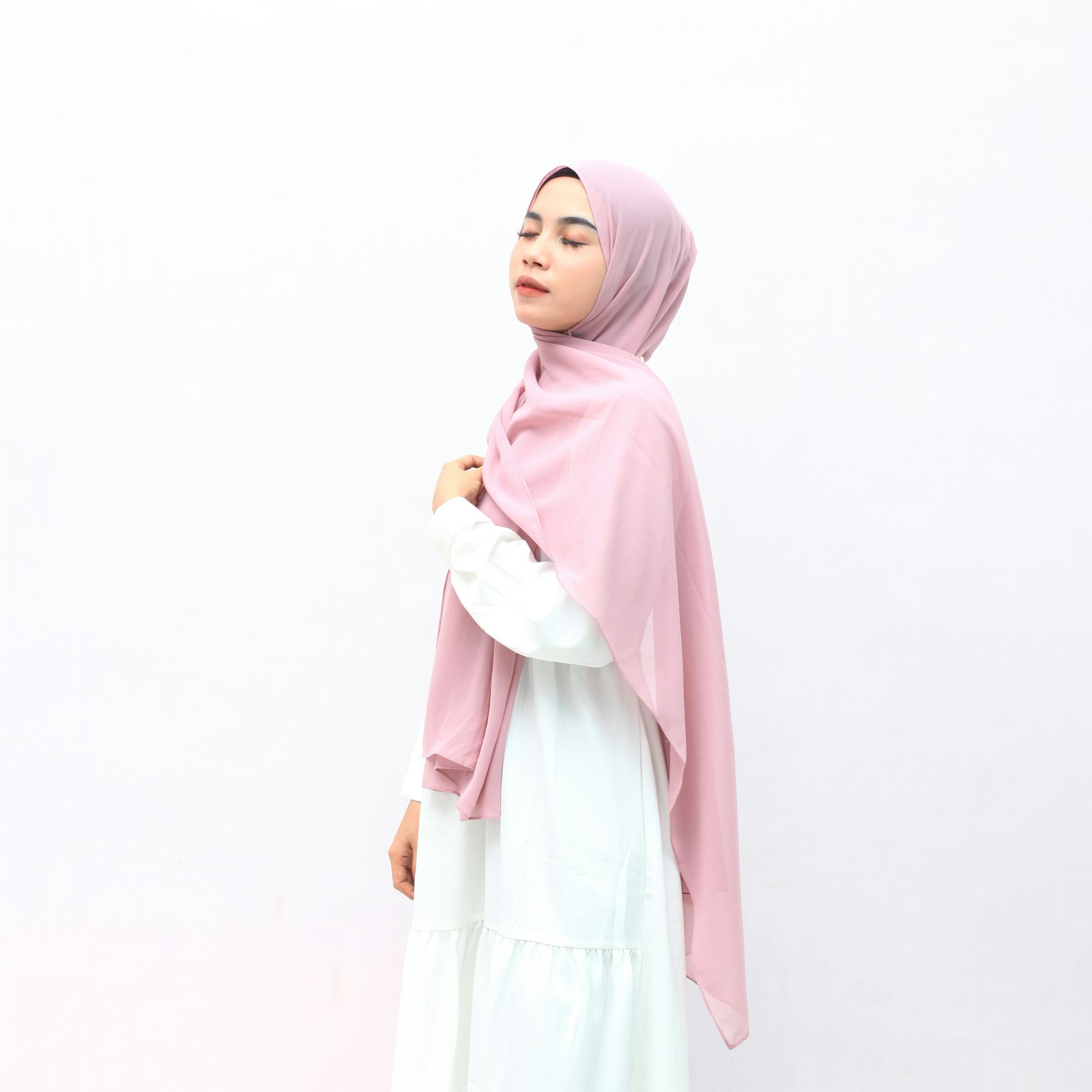 Perempuan memakai hijab instan merah muda dan gamis putih