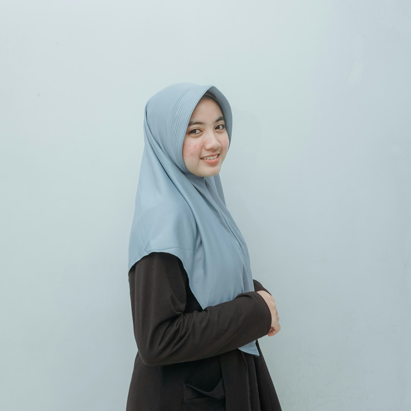 Perempuan memakai hijab segi empat biru muda
